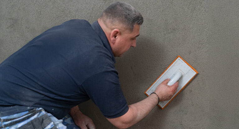 Technicien HUMY appliquant un enduit sur mur de cave